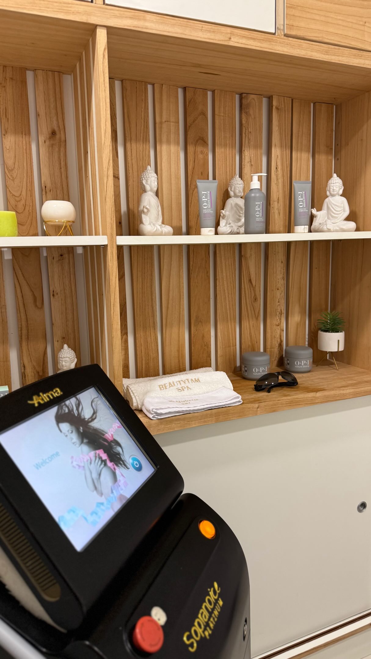 La cabina de depilación láser: estantes de madera con budas, cremas OPI Nature Strong y toallas bordadas BEAUTYTAM SPA